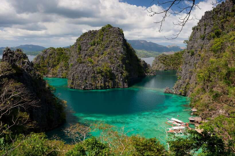 From Coron: Twin Lagoon and Skeleton Wreck Cruise with Lunch - Malcapuya Island: cliffs, open water, and a beach rhythm